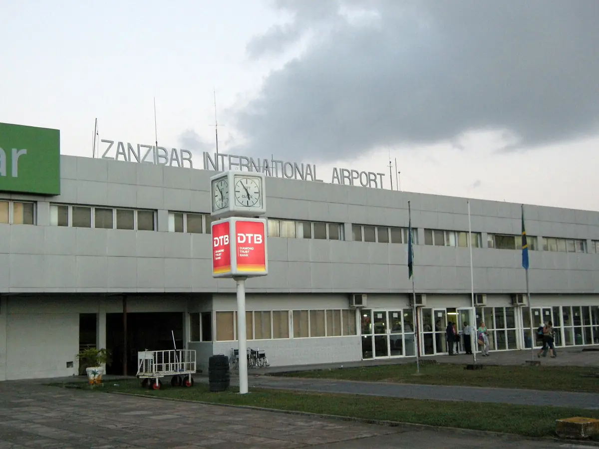 Front of the airport terminal building under a partly cloudy sky