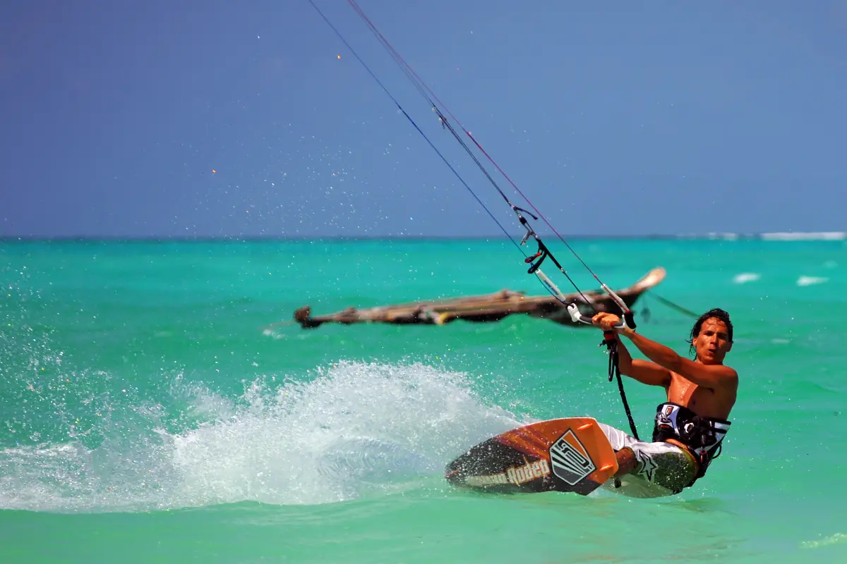 Kitesurfer carving a turn across turquoise lagoon water off Zanzibar
